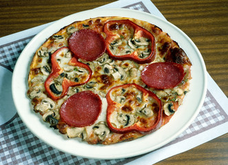 Una pizza con tomate, queso, salami,  pimientos y chamiñones. 