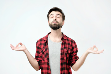 Relaxed carefree man meditates, tries to relax after long hours of studying, concentrates on something. Using yoga in everyday life