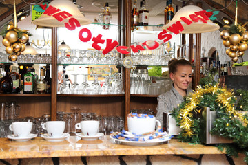 Barmanka za bufetem w knajpie robi kawe, Boże Narodzenie.