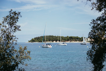 Fototapeta na wymiar Sail boats and clear blue water in a Croatian bay, golden cape