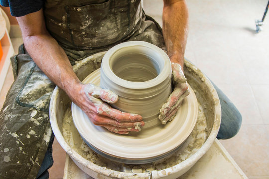 Artist potter in the workshop creating a ceramic vase. Hands detai closeup. Twisted potter's wheel. Small artistic craftsmen business concept. 