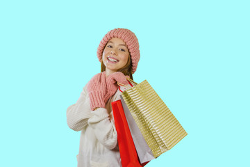 Fototapeta premium Cute young red-haired girl with a knitted pink hat and colorful packages holding them on her shoulder, smiling and looking into the camera, isolated background
