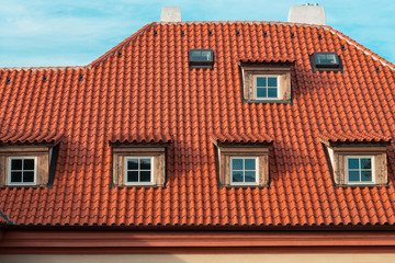 Beautiful old house with orange roof with multiple windows and  blue sky. Part of old town in Prague.