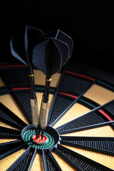Three darts in bullseye of dartboard