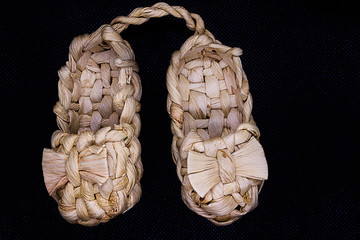 Pair of wicker bast shoes on a black background