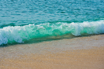 Waves with foam hitting sand on the tropical beach texture.