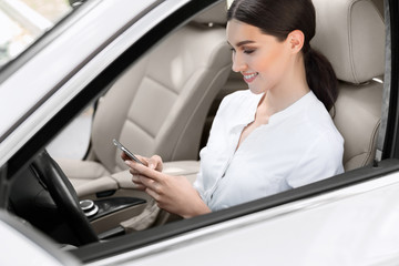 Business woman sitting in car, using mobile phone