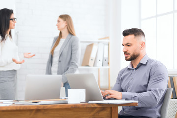 Obraz premium Businessman using laptop while coworkers interacting on background