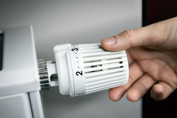 hand adjusting temperature on radiator. energy saving concept