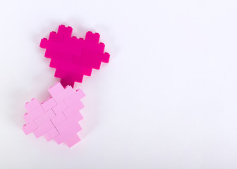 The bricks of the plastic constructor in the form of hearts are red, magenta, pink. White background.