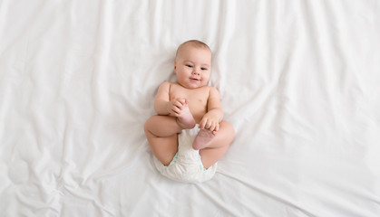 Cute baby lying on bed at home, top view