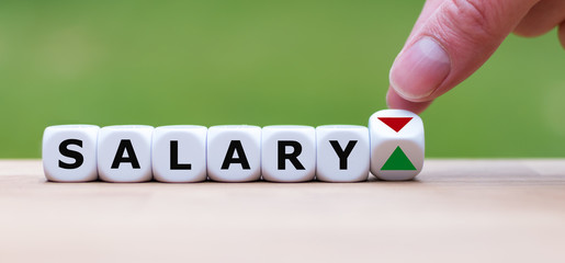 Hand is turning a dice and changes the direction of an arrow symbolizing that the personal salary is going up instead of down (or vice versa)