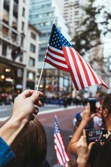 partial view of man holding american flag during parade on street in new york, usa