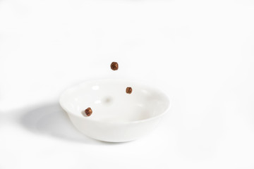 Chocolate balls falling in a white plate.