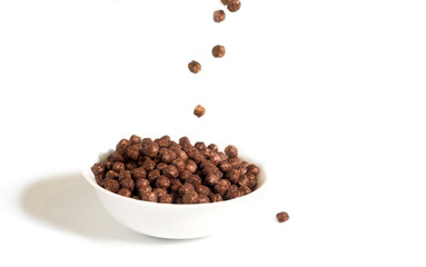 Chocolate balls falling in a white plate. On a white background.