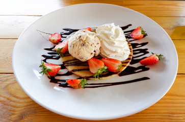 Strawberry pancake Chocolate chip ice cream Delicious dessert fresh strawberries fruit on pancake with vanilla ice cream scoop and whip cream pour chocolate
