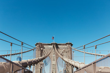 Fototapeta premium brooklyn bridge with american flag on clear blue sky background, new york, usa