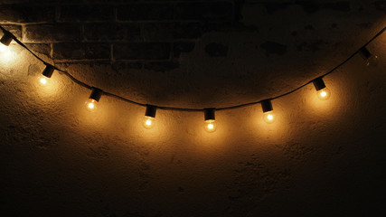 Yellow light bulbs hanging infront of a brick wall.
