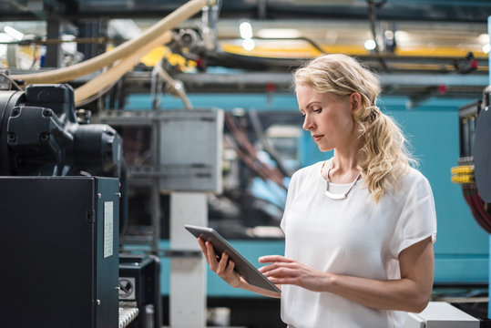 Woman with bleached hair using digital tablet in factory