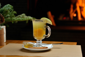 berry tea with lemon in a transparent glass on the background of the fireplace, Christmas tea
