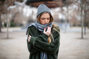 Young woman wrapping in scarf in autumn park