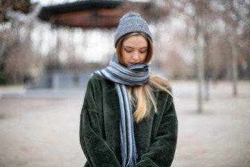 Blurred young woman wrapping in scarf in autumn park