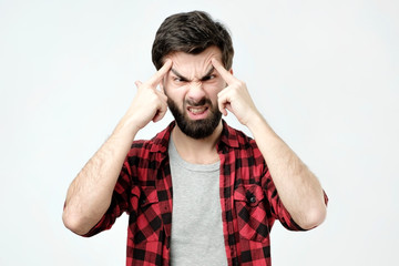 Portrait of concentrated man, lifts eyebrows with fingers. Negative facial emotion.