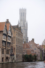Fototapeta na wymiar Tourists doing boat trip on canal of Bruges surrounded by flemish buildings in Belgium