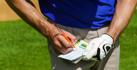 Golfer keeping score on scorecard.