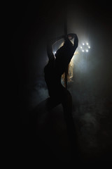 Naklejka na ściany i meble Pretty woman dancing in a pole dance studio