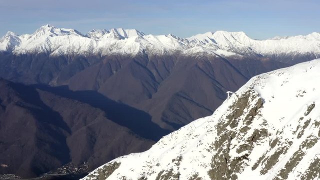 Beautiful landscape mountains with snowy peaks on sky background drone view. View from above high snowy mountains on blue sky background. Winter mountain ridge in valley