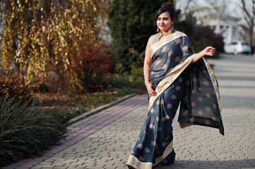 Elegant brunette south asian indian girl in saree walking outdoor.