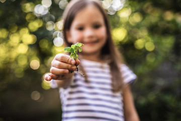 Preteen child holding new plant while gardening