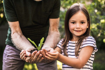 Girl with grandfather holding new plant grown