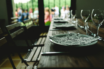 Wooden tables with cutlery plates and backlit glasses without anyone.