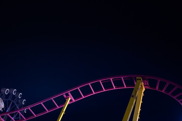 Rails of a roller coaster, blue night sky background.