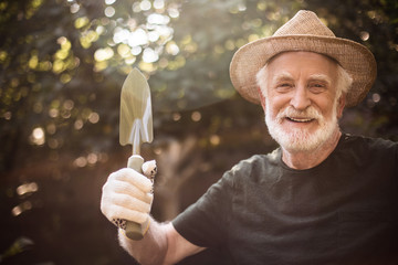 Aged male horticulturist is showing garden equipment