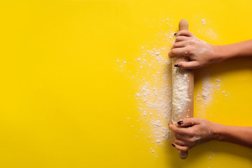 Girl hands keep rolling pin with flour on yellow background. Bake menu, recipe, homemade pastry...