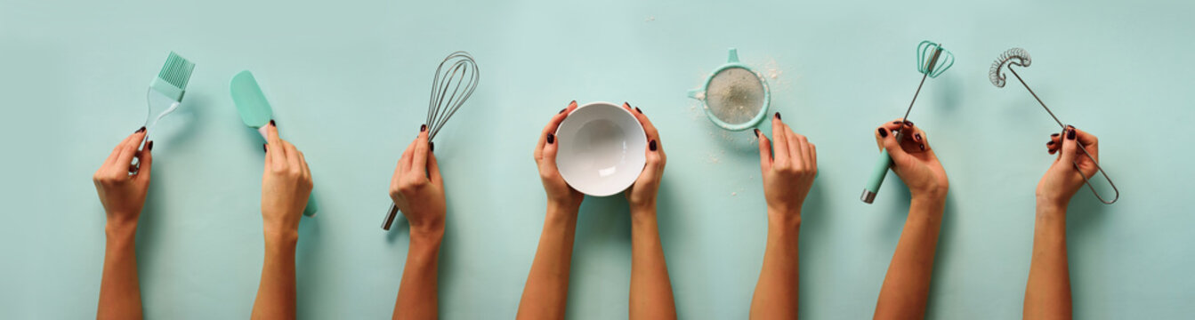Female hands holding kitchen tools, sieve, rolling pin, bowl, sieve, brush, whisk, spatula for baking and cooking over pastel blue background. Food frame, bake concept with copy space