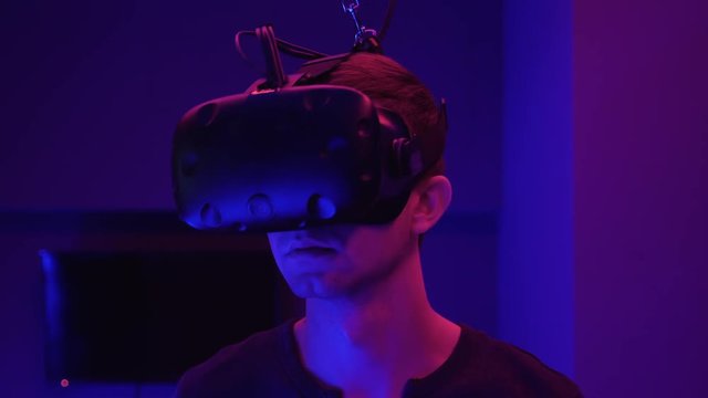 Young man in head-mounted display looks around, virtual reality