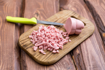 Chopped boiled sausage on a wooden board.