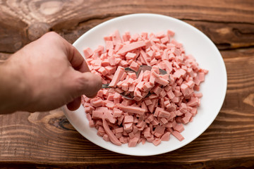 Finely chopped boiled sausage on a white plate.