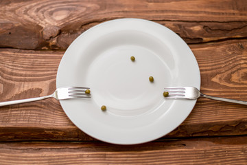 Diet concept. Several peas lying on a white plate. Restriction in nutrition.