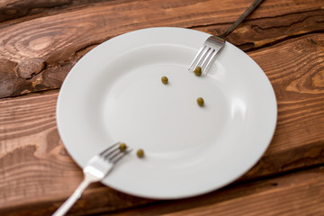 Diet concept. Several peas lying on a white plate. Restriction in nutrition.