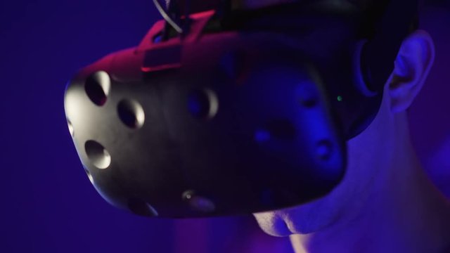 Young man in head-mounted display looks around, virtual reality