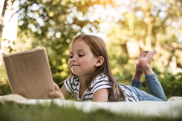 Girl with book on blanket in park