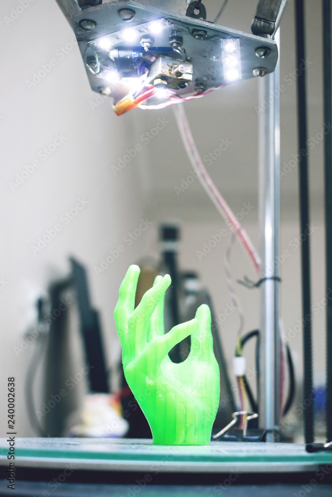 Poster green plastic 3d printed human hand stands in three-dimensional printer. object model printed on aut