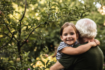 Pretty little girl with her grandfather in garden