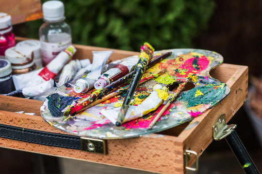 the artist's palette with paints and brushes on the easel