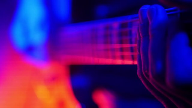 Guitarist plays on his guitar in the smoke in bright neon lighting.